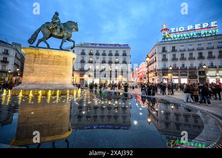 La statua del re Carlo III con il famoso cartello pubblicitario Tio Pepe sullo sfondo nella Puerta del Sol, Madrid, Spagna. Foto Stock