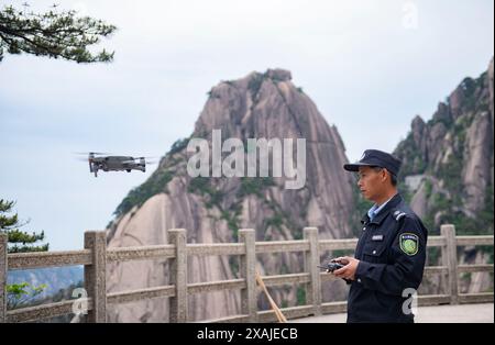 (240607) -- HEFEI, 7 giugno 2024 (Xinhua) -- Ding Ding controlla l'ambiente circostante del pino di benvenuto con un drone nella zona panoramica del monte Huangshan nella provincia di Anhui della Cina orientale, 4 giugno 2024. Il Guest-Greeting Pine e' un famoso punto di riferimento sul Monte Huangshan. Il pino alto 10 metri, le cui radici sono sgorgate dalle rocce del sito patrimonio dell'umanità dell'UNESCO, si trova a un'altitudine di oltre 1.600 metri. La sua caratteristica più riconoscibile è un lungo ramo che si estende come un braccio allungato in un gesto accogliente. Negli anni '1980 fu creato un post per supervisionare il Pine Guest-Greeting, r Foto Stock