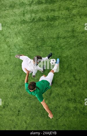 Vista aerea. Due giovani atleti sul campo che giocano a calcio in movimento. Giocatori di calcio in un parco giochi lussureggiante. Foto Stock