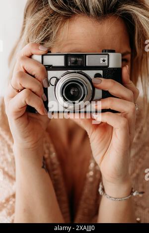 Primo piano di una donna che tiene in mano una fotocamera d'epoca Foto Stock