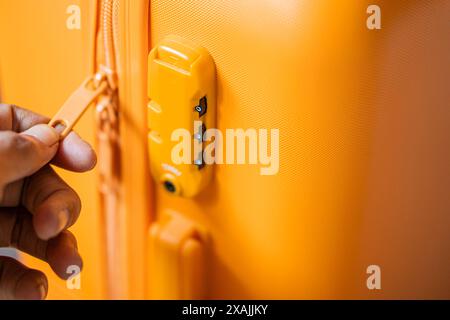 Primo piano di una persona che imposta una serratura a combinazione su una valigia gialla. Foto Stock