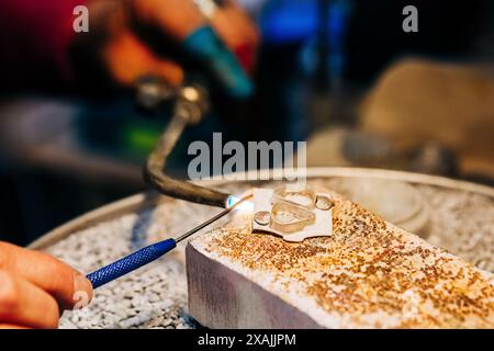 Infilare le mani di gioiellieri utilizzando una torcia per gioielli per saldare Foto Stock