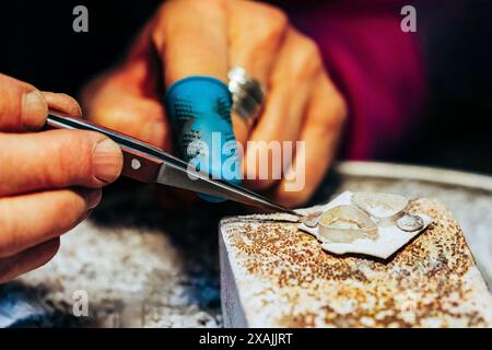 Primo piano di gioiellieri che saldano a mano sul banco di lavoro Foto Stock