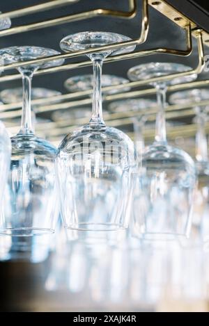 Primo piano di bicchieri da vino sospesi elegantemente capovolti al bar. Foto Stock