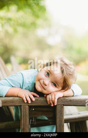 Una bambina con gli occhi blu si siede nel cortile Foto Stock