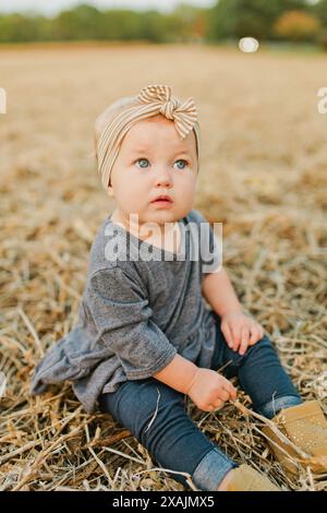 La ragazza con gli occhi blu si siede in campo con l'arco sulla testa Foto Stock