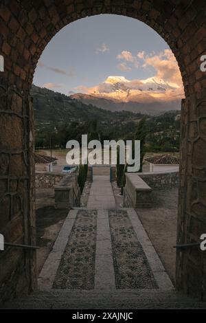 Vista delle montagne di Huascaran attraverso l'arco in pietra al tramonto. Foto Stock