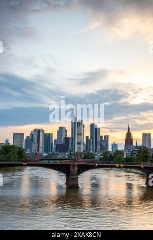 Vista da un ponte, sul fiume meno, su uno skyline nel quartiere finanziario sullo sfondo il sole sta tramontando. Crepuscolo a Francoforte sul meno, Assia Germania Foto Stock