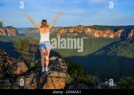 Giovane donna caucasica bionda che ammira la vista sul Parco Nazionale delle Blue Mountains dal Pulpit Rock Lookout nel nuovo Galles del Sud, Australia Foto Stock