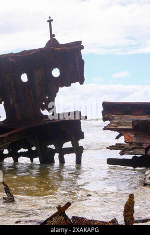 Rusty pezzo sbriciolato del relitto della SS Maheno metà sepolto nella sabbia della spiaggia di 75 miglia sulla costa orientale di Fraser Island nel Queensland, Austra Foto Stock