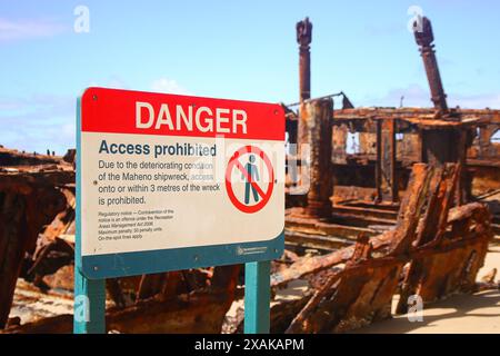 Cartello di pericolo che proibisce l'accesso al relitto della SS Maheno sepolto per metà nella sabbia della spiaggia di 75 miglia sulla costa orientale dell'isola Fraser a Queenslan Foto Stock