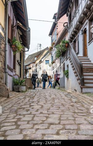 Europa, Francia, Grand Est, Alsazia, Eguisheim, turisti in una stretta strada acciottolata Foto Stock