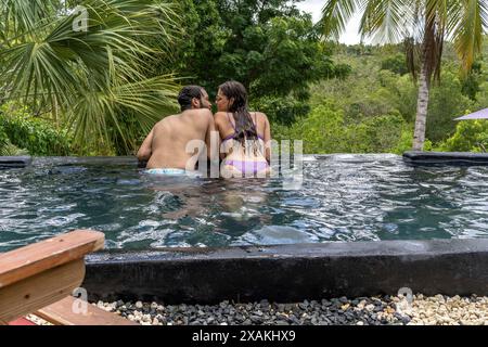 Nord America, Caraibi, grandi Antille, isola di Hispaniola, Repubblica Dominicana, provincia di la Altagracia, la Romana, giovane coppia nella piscina dell'Eco River House Glamping Foto Stock