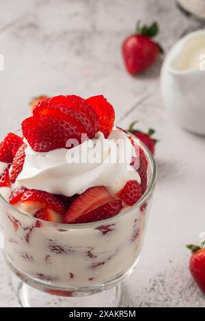 Fragole con panna in una tazza di vetro sul tavolo di cemento. Copia spazio. Foto Stock