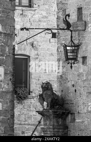 Una statua di leone e un antico lampione d'epoca nella città di Volterra, Italia Foto Stock