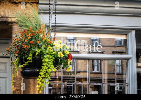 Riflessi di Sherborne High Street in una vetrina da caffe', con un colorato cestino appeso. Scena astratta e urbana. Cartello Cafe. Concetto. Foto Stock