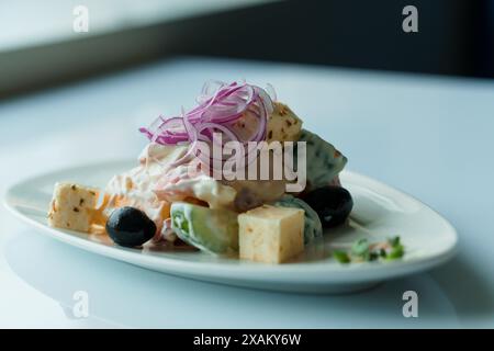 Insalata con erbe aromatiche, formaggio duro, olive, pomodori ciliegini, cipolle, cetrioli e lattuga Foto Stock