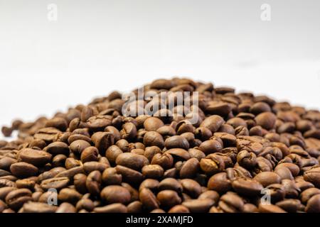 Mani esperte tostano i chicchi di caffè su una fiamma libera, rilasciando il loro aroma ricco. I chicchi si spezzano, segnalando l'erogazione perfetta Foto Stock
