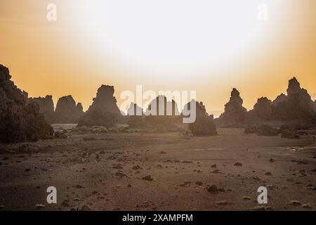 Paesaggio lunare di camini di pietra calcarea formazioni rocciose geologiche in un tramonto raggi sul fondo del lago salato essiccato Abbe, regione di Dikhil, Gibuti Foto Stock