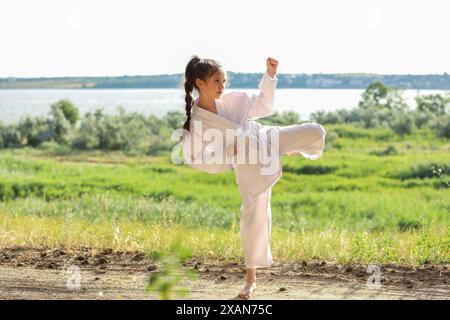 Carina bambina in kimono pratica karate all'aperto Foto Stock