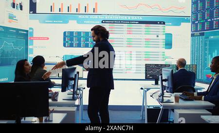 Responsabile finanziario che informa i membri del suo team sui nuovi obiettivi aziendali, presentando il loro schema di budget con le spese. Allocazione delle risorse e pianificazione dei progetti nella sala di controllo. Telecamera B.. Foto Stock