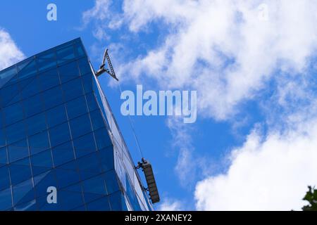 Persone che lavorano insieme all'aperto puliscono finestre su alti edifici, con sfondo blu nuvoloso del cielo, Melbourne Australia. Foto Stock