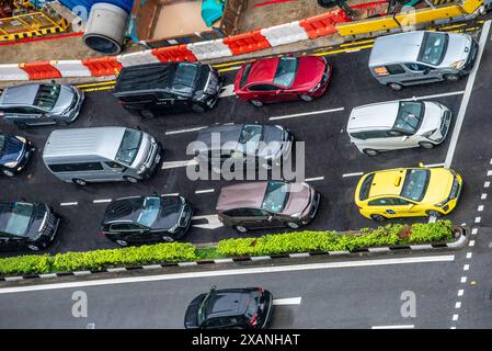 Guardando in basso su un importante incrocio stradale nel centro di Singapore con il traffico e si fermò ad un incrocio o ad un semaforo sotto la pioggia Foto Stock