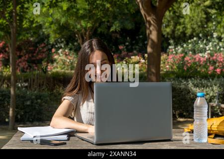 Giovane ragazza del college seduta a un tavolo del campus, che partecipa a una riunione virtuale con il suo laptop. Vita studentesca, tecnologia, istruzione, inizio Foto Stock