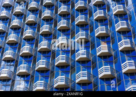 Sfondo astratto caratterizzato da uno schema di balconi ripetuti sulla facciata di un moderno edificio in vetro, che crea un effetto visivo impressionante. Foto Stock