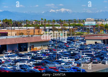 Los Angeles, California - 9 aprile 2024: Parcheggio per noleggio auto densamente affollato vicino all'aeroporto di Los Angeles con palme e montagne sullo sfondo. Foto Stock
