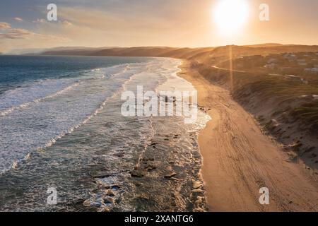 Vista aerea delle onde dell'oceano su una costa sabbiosa al tramonto all'Aireys Inlet sulla Great Ocean Road a Victoria, Australia Foto Stock