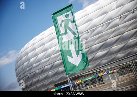 Monaco, Germania. 7 giugno 2024. Una bandiera con il simbolo di una via di fuga è visibile di fronte alla Munich Football Arena il 7 giugno 2024 in vista di una conferenza stampa per presentare il concetto di sicurezza per il Campionato europeo di calcio nella Munich Football Arena di Monaco (Baviera). Il campionato europeo di calcio prende il via nello stadio di calcio il 14 giugno con la partita di apertura Credit: Matthias Balk/dpa/Alamy Live News Foto Stock