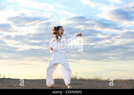 Carina bambina in kimono pratica karate all'aperto Foto Stock