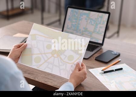 Cartografo che lavora con mappe catastali al tavolo di legno in ufficio, primo piano Foto Stock