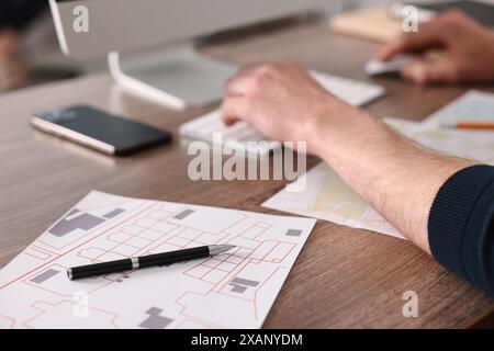 Cartografo che lavora con mappe catastali al tavolo di legno in ufficio, primo piano Foto Stock