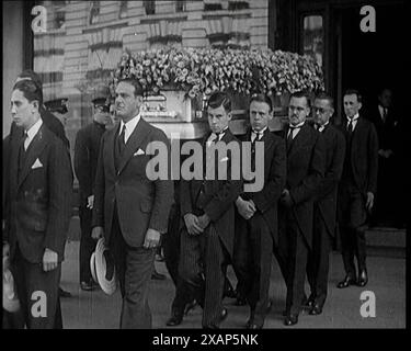 Un gruppo di perfidi tra cui l'attore Douglas Fairbanks che partecipa al funerale di Rodolfo Valentino, 1926. Era l'idolo dello schermo di milioni, di quanti milioni avremmo scoperto solo... quando un giorno nel 1926, inaspettatamente, morì. Amici famosi come Douglas Fairbanks camminavano con la bara, e per il numero incalcolabile di donne del mondo, era come se i loro cuori si fossero fermati...100.000 fiancheggiavano la strada...". Da "Time to Remember 1926 - Short Sharp Shower"- Reel 1; un documentario sul 1926 - General Strike, politica internazionale, danza, meteo e record break Foto Stock