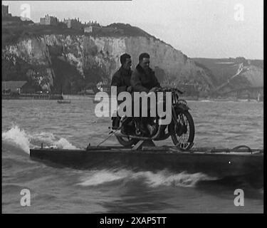 Due civili maschi in sella a una motocicletta su un galleggiante attraverso il Canale della Manica, 1929. "Due ragazzi brillanti hanno attraversato il Canale in moto". Pubblicità: I galleggianti erano montati su una Model e Ariel da 499 cc standard, con una ruota dentata aggiuntiva sul mozzo posteriore che azionava una piccola elica. I due dipendenti dell'Ariel attraversarono il Canale della Manica da dover a Calais in poco meno di quattro ore. Da "Time to Remember - 1929 The Time of the House at Bognor" - Reel 1; un documentario sul mondo nel 1929. Malattia di re Giorgio V &amp; depressione economica. Foto Stock