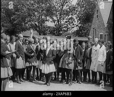 Un gruppo di giovani civili femminili che indossano uniformi scolastiche in piedi davanti a una scuola, 1920 anni Da "Time to Remember - Teenage Flapper", anni '1920 (Reel 2); un dcumentary sulla vita delle donne negli anni '1920 - grande commento di Joyce Grenfell. Foto Stock