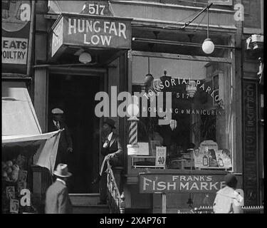 Civili americani fuori da un parlour di bobbing e manicure, 1930 anni "Il crimine del secolo" - il caso di rapimento Lindbergh, USA. "L'argomento del giorno, ogni giorno, ...in le sedie nei barbieri, è Hauptmann colpevole o no?" Il testo sulla finestra recita: "Salone tonsoriale - bobbing &amp; manicuring". Da Time to Remember - The Tough Guys, 1930s (Reel 3); film documentario, principalmente sulla vita in depressione e gangster-hit America. Foto Stock