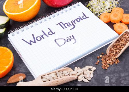 Notepad con iscrizione Giornata Mondiale della tiroide e miglior cibo contenente minerali naturali e vitamine per la tiroide sana Foto Stock