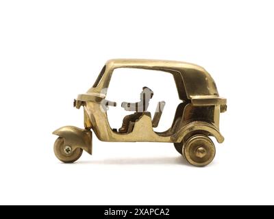 un modello giocattolo vintage di un veicolo a tre ruote con risciò automatico realizzato in metallo di ottone dorato isolato in bianco Foto Stock