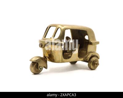 un modello giocattolo vintage di un veicolo a tre ruote con risciò automatico realizzato in metallo di ottone dorato isolato in bianco Foto Stock