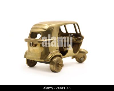 un modello giocattolo vintage di un veicolo a tre ruote con risciò automatico realizzato in metallo di ottone dorato isolato in bianco Foto Stock