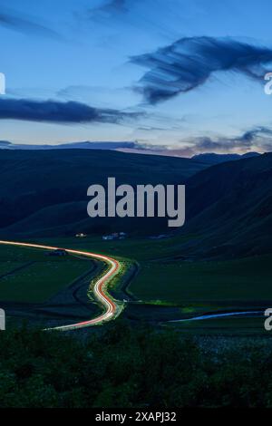 Islanda all'ora blu con Orange Horizon con Long Exposure Car Light Trails on a Road and River Foto Stock