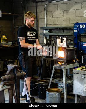 Il maestro fabbro lavora con la lama di metallo utilizzando la fornace antincendio presso l'Iron Mountain Craft Shop a Pigeon Forge, Tennessee. Foto Stock