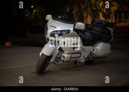 Motocicletta bianca nel parcheggio. Moto di notte. Trasporto personale. Parcheggio in città. Foto Stock