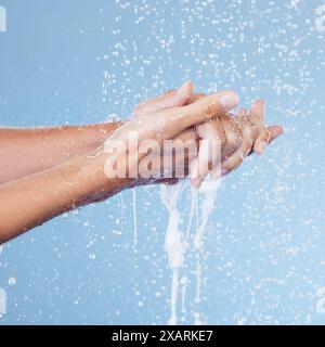 Persona, mani e acqua per lavarsi in studio, bellezza e cura della pelle su sfondo blu. Palme, detergenti e liquidi per cosmetici o. Foto Stock