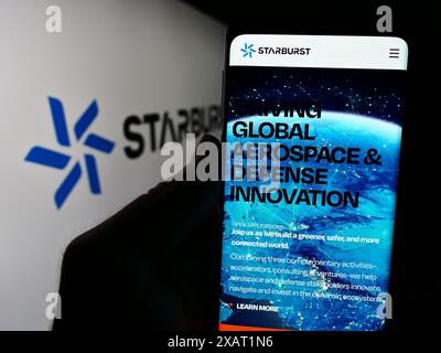 Persona che detiene il cellulare con la pagina web della società di venture capital statunitense Starburst Aerospace Ltd. Davanti al logo. Messa a fuoco al centro del display del telefono. Foto Stock