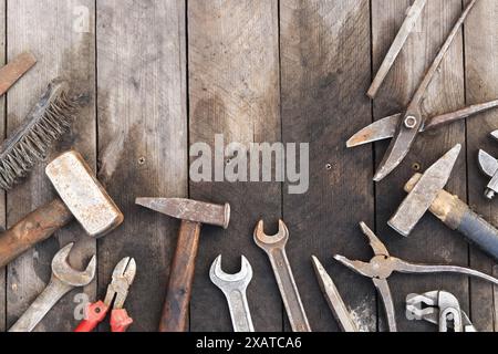 Vecchie attrezzature su sfondo in legno a tavola, vista dall'alto. Martelli, lima piatta, cesoie per stagno, spazzola, chiave regolabile e chiave. Strumento manuale. Giorno del costruttore o. Foto Stock
