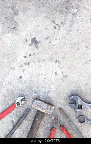 Vecchi utensili di lavoro su una superficie in calcestruzzo, vista dall'alto. Martello, tronchesini laterali, lima piatta, chiave regolabile e chiave. Strumento manuale. Festa dei costruttori o di papà Foto Stock